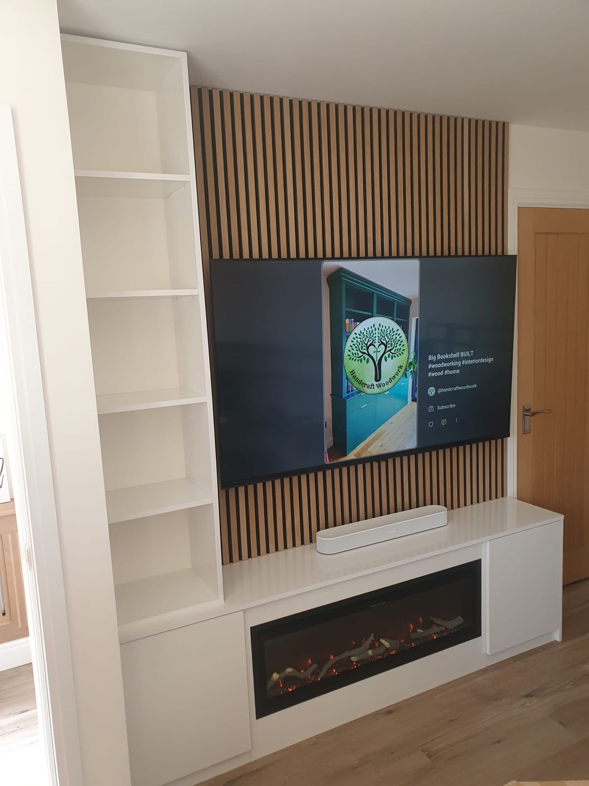 Media wall with oak slat acoustic panelling, inset electric fire and fitted bookcase