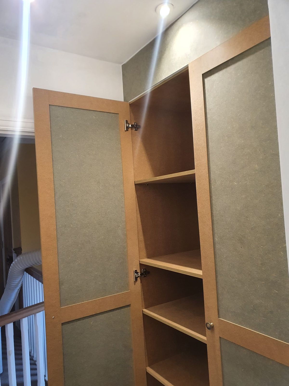 Fitted wardrobe carcass with hanging rail and shelving, door open on concealed hinges